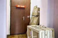 Packed paintings in wooden crates and cardboard boxes near the door with a sign 