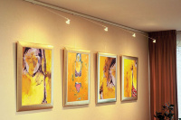 Gallery picture hanging system with integrated lighting and four framed paintings on a wall