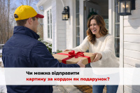 Кур’єр у синій куртці та жовтій кепці вручає подарункову коробку з червоною стрічкою усміхненій жінці на фоні білого будинку взимку