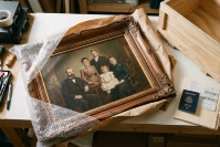 Старинний сімейний портрет поруч із пакувальними матеріалами, дерев’яним ящиком і документами для перевезення