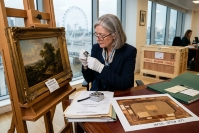 Expert examining an antique painting and documents before international transport