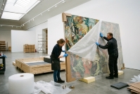 Art handlers wrapping a large painting in protective material for international fine art shipping