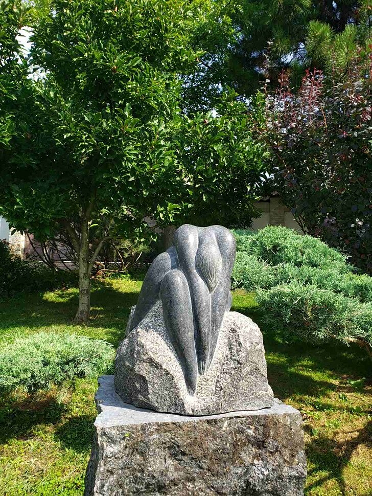 гранитная скульптура, девушка склонилась вперед, закрывшись от всего мира, погружаюсь в свои мысли