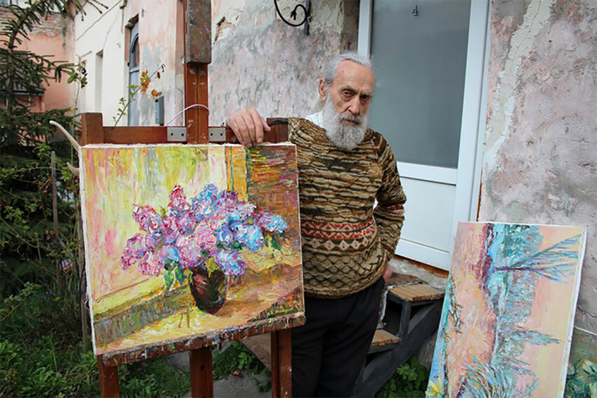 Художник Виктор Макаров возле своих картин
