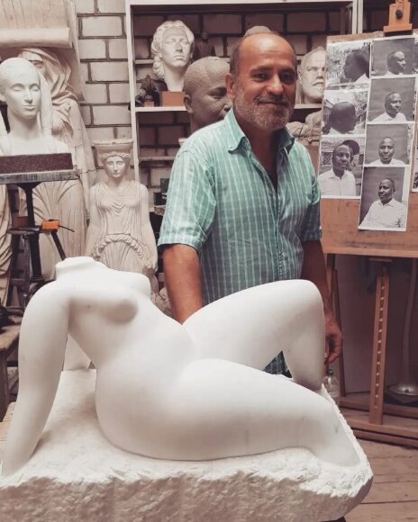 скульптор Владимиров Алексей в своей мастерской рядом с мраморной скульптурой женщины